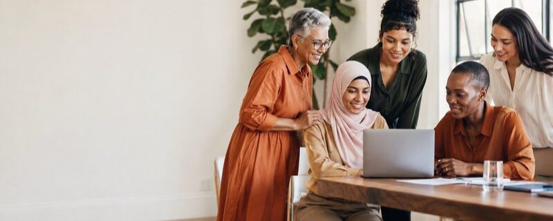 Women collaborating around a laptop in a bright workspace